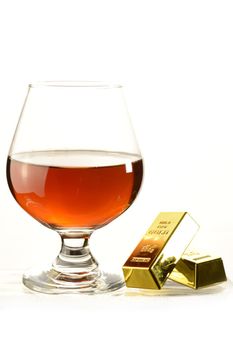 A glass of Cognac and gold bullion bars over a white background.