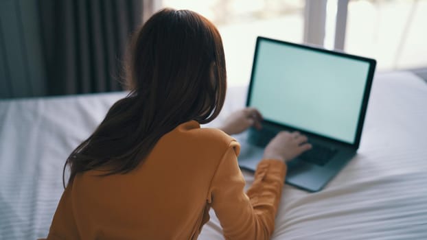 woman in bedroom lies on bed in front of laptop communication technology. High quality photo