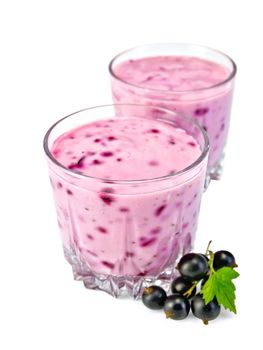 Milkshake in two low glassful, berries and green leaves of black currant isolated on a white background