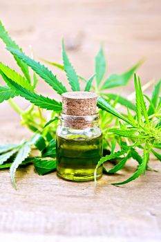 Hemp oil in a glass bottle, leaves and stalks of cannabis on the background of old wooden boards