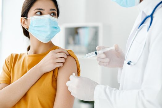 the patient in the hospital and the doctor in protective gloves inject the vaccine into the woman's shoulder. High quality photo