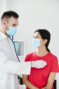 doctor with a stethoscope examines a patient wearing a medical mask breathing . High quality photo