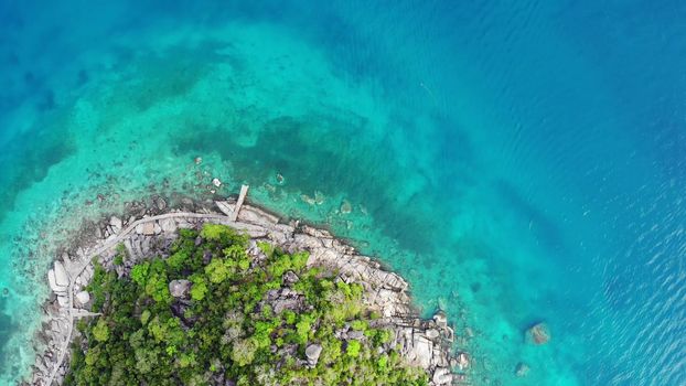 Calm colorful azure turquoise sea near tiny tropical volcanic island Koh Tao, unique small paradise Nang Yuan. Drone view of peaceful water near stony shore and green jungle on sunny day in Thailand