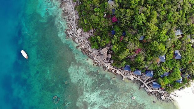 Calm colorful azure turquoise sea near tiny tropical volcanic island Koh Tao, unique small paradise Nang Yuan. Drone view of peaceful water near stony shore and green jungle on sunny day in Thailand