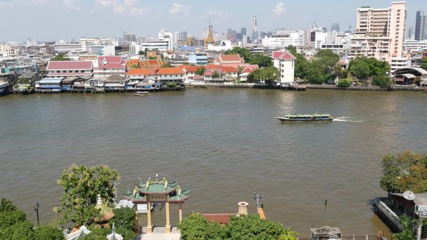 Oriental boat floating on river in Krungthep city. Modern transport vessel floating on calm Chao Praya river on sunny day in Bangkok near chinatown. Panorama.
