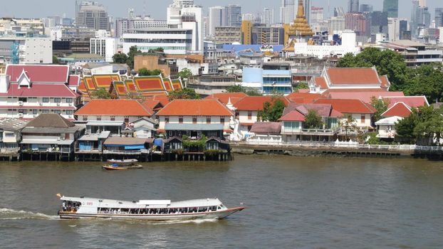 Oriental boat floating on river in Krungthep city. Modern transport vessel floating on calm Chao Praya river on sunny day in Bangkok near chinatown. Panorama.
