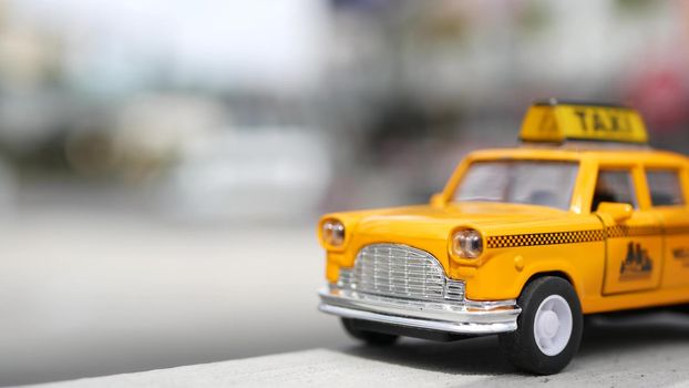 Yellow vacant mini taxi cab close up, Harmon corner, Las Vegas, USA. Small retro car model on defocused background. Little iconic auto toy as symbol of transport in soft focus. Blurred shopping mall.