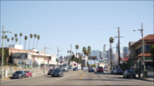 Driving on downtown streets of Los Angeles, California USA. Defocused view from car thru glass windshield on driveway. Blurred road with vehicles in Hollywood. Camera inside auto, LA city aesthetic.