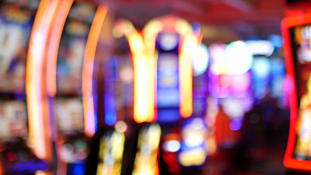 Defocused slot machines glow in casino on fabulous Las Vegas Strip, USA. Blurred gambling jackpot slots in hotel near Fremont street. Illuminated neon fruit machine for risk money playing and betting.