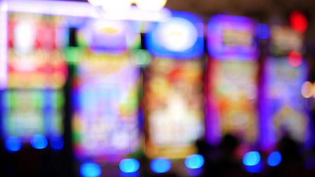 Defocused slot machines glow in casino on fabulous Las Vegas Strip, USA. Blurred gambling jackpot slots in hotel near Fremont street. Illuminated neon fruit machine for risk money playing and betting.