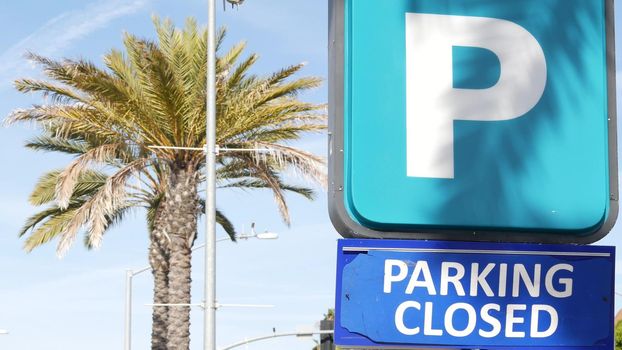 Parking lot sign as symbol of traffic difficulties and transportation issues in busy urban areas of USA. Public paid parking zone in downtown of San Diego, California. Limited space for cars in city.