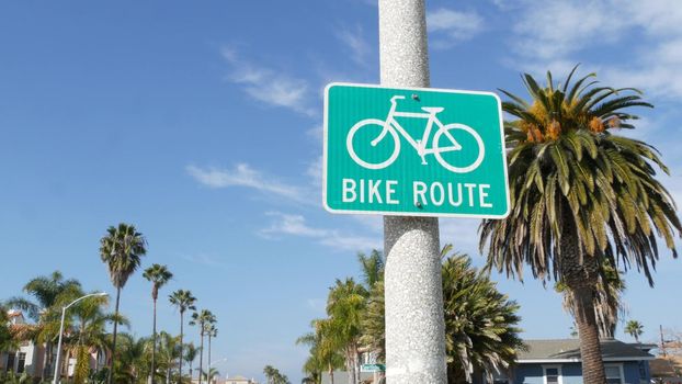 Bike Route green road sign in California, USA. Bicycle lane singpost. Bikeway in Oceanside pacific tourist resort. Cycleway signboard and palm. Healthy lifestyle, recreation and safety cycling symbol.