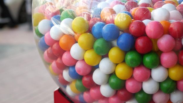 Colorful gumballs in classic vending machine, USA. Multi colored buble gums, coin operated retro dispenser. Chewing gum candies as symbol of childhood and summertime. Mixed sweets in vintage automate.