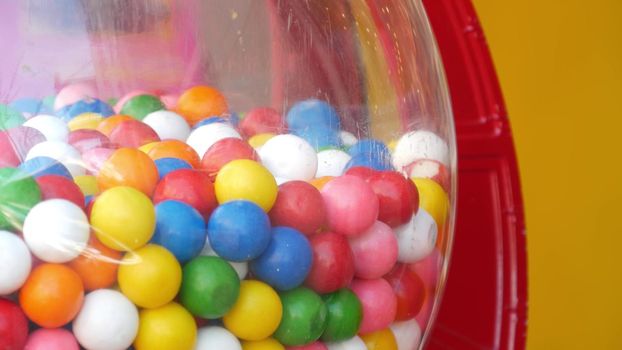 Colorful gumballs in classic vending machine, USA. Multi colored buble gums, coin operated retro dispenser. Chewing gum candies as symbol of childhood and summertime. Mixed sweets in vintage automate.