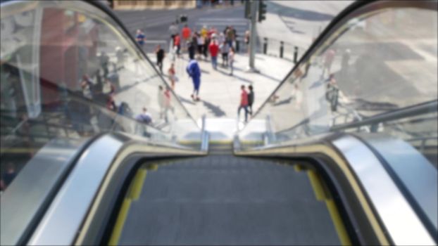 Perspective view thru escalator, defocused unrecognizable group of people on road intersection crosswalk on Strip of Las Vegas, USA. Anonymous blurred pedestrians on walkway in crowded urban downtown.