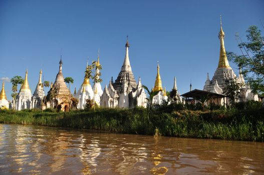 Ancient temple on shore of lake, Landscape of brown water of lake Inle with plenty of sacred temple stupas and payas on shore. Inle, Myanmar,Burma.