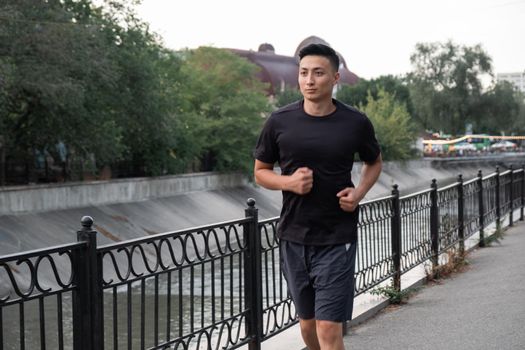 An Asian man running in the city, in the evening. Kazakhstan