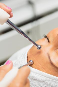 The girl is undergoing a procedure in a beauty salon. Anti-aging treatment with microcurrent drugs