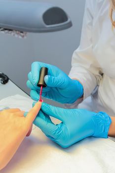 In a beauty salon, a woman is given a manicure, a nail is painted with varnish. Close-up.