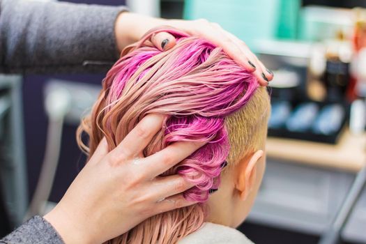 Hair dyeing for a girl in a beauty salon, long hair pink. Hair care