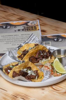 Two roast beef tacos with coriander and onion in corn tortillas.