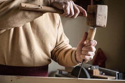 Carpenter working with a wooden hammer and a gouge