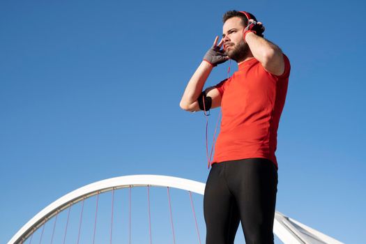 Closeup shot of a young male in red headphone listening to music while working out in the street