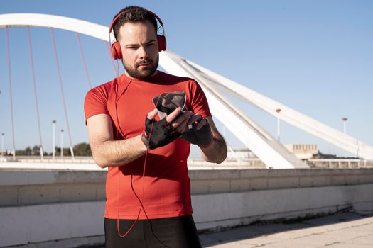 Closeup shot of a male in red headphones using his mobile while jogging in the street