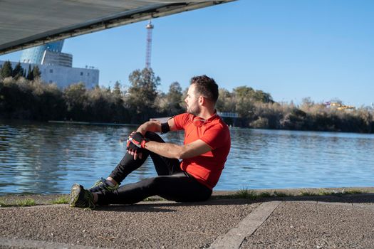 Closeup shot of a young male in sports costume sitting on the body of the river