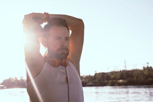 young man stretching out his arms with headphones on.