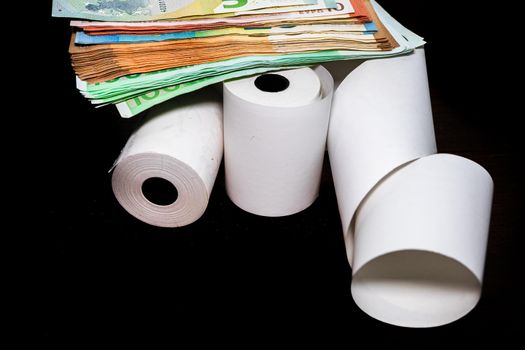 Roll of cash register tape and money isolated on table. Planning savings, spending money or business concept.