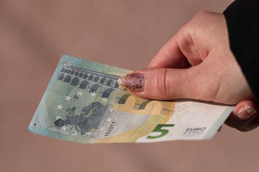 woman hands giving money like a bribe or tips. Holding EURO banknotes on a blurred background, EU currency