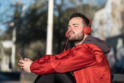 young man in sportswear listening to music with a pair of headphones