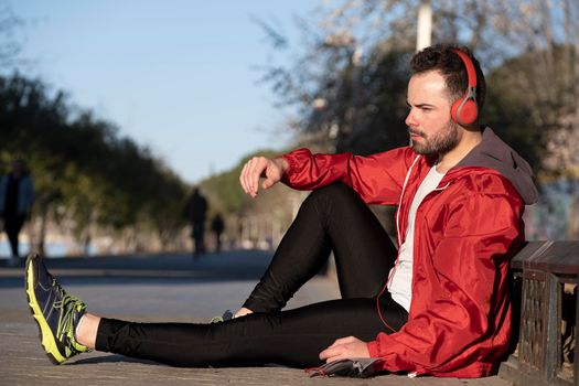 young man in sportswear listening to music with a pair of headphones