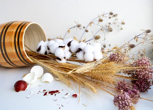 Easter. Still life with eggshells, clay barrel and dried flowers on a white background.