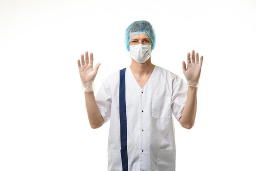 A male doctor stands with his hands raised up, gloves are on, a mask and a hat are on his head