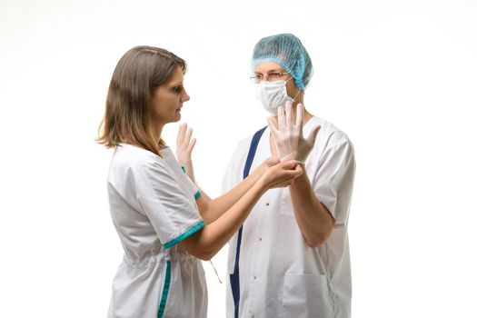 A nurse puts sterile medical gloves on the surgeon's hands