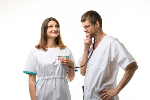 The doctor listens with interest to the girl's heart with a phonendoscope