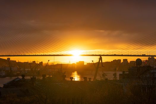 Vladivostok, Russia. The city skyline in the sunset light. Silhouettes of the port and the Golden bridge
