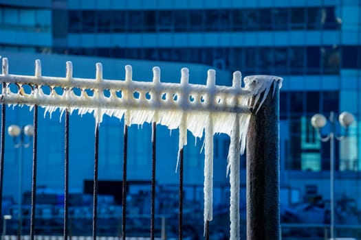 Metal construction in ice on a blurred background.