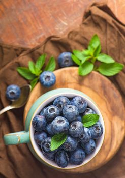 Fresh blueberry in a cup with leaves of mint.