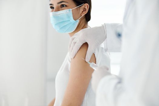 doctor in protective gloves injects a vaccine into the shoulder of a woman patient. High quality photo