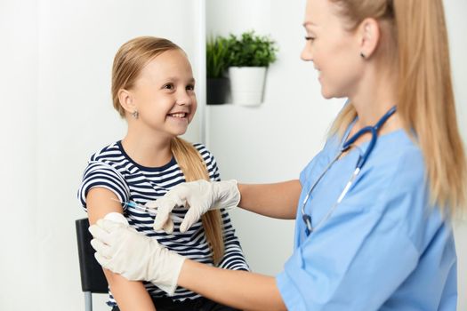 woman doctor in a blue coat injecting a child into the hand. High quality photo