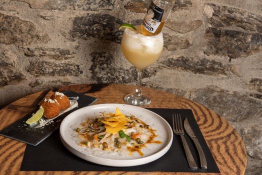 Arinsal, Andorra: 2021 February 4: White plate with Cod Carpaccio with chili vinaigrette, pumpkin seeds and chips.