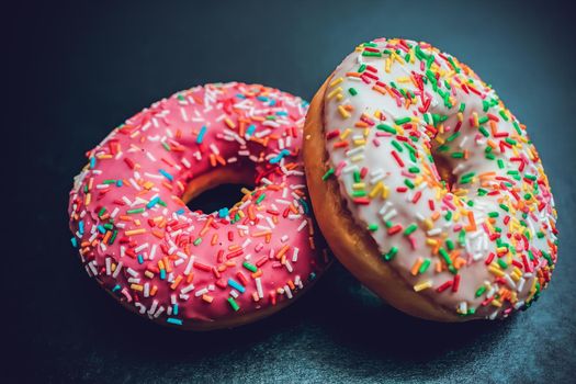 Fresh, tasty and sweet donuts with different glaze and different fillings on a dark background