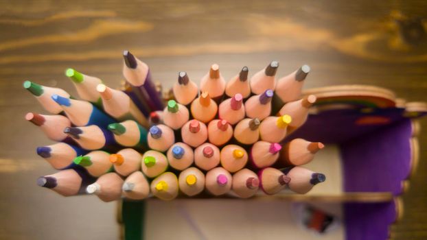 A set of colored pencils, stationery. A lot of multicolored pencils on the table.