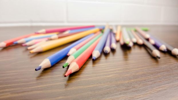 A set of colored pencils, stationery. A lot of multicolored pencils on the table.