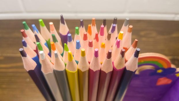 A set of colored pencils, stationery. A lot of multicolored pencils on the table.