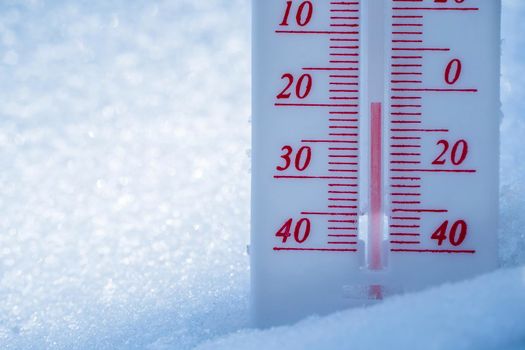 The thermometer lies on the snow in winter showing a negative temperature. Meteorological conditions in a harsh climate in winter with low air and ambient temperatures.Freeze in wintertime