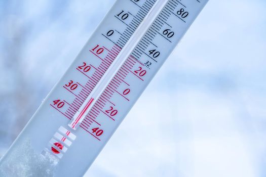 The thermometer lies on the snow in winter showing a negative temperature. Meteorological conditions in a harsh climate in winter with low air and ambient temperatures.Freeze in wintertime